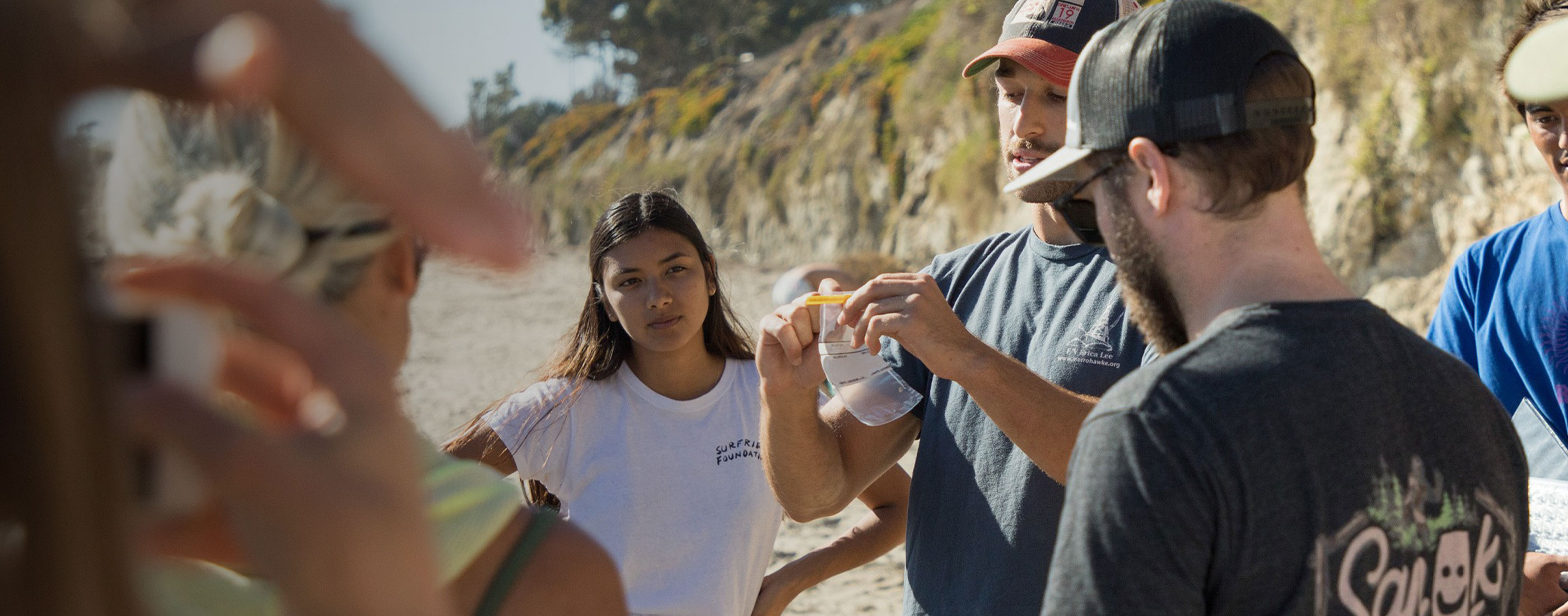 Volunteer holds up empty sample bag in front of a circle of people.